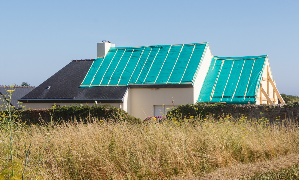 House with the Roof Covered by a Tarpaulin
